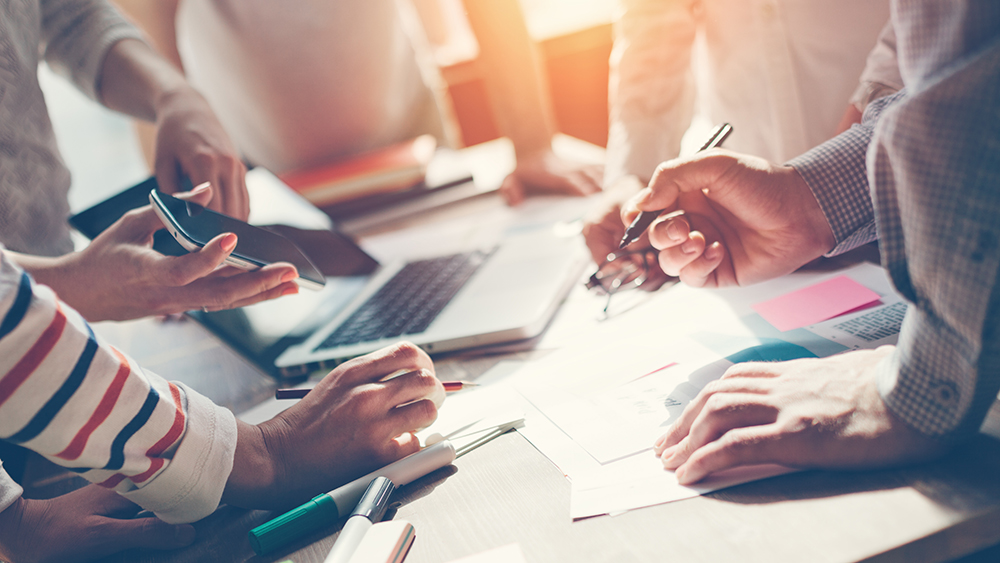 Ihmisten käsiä, puhelin ja kirjoja