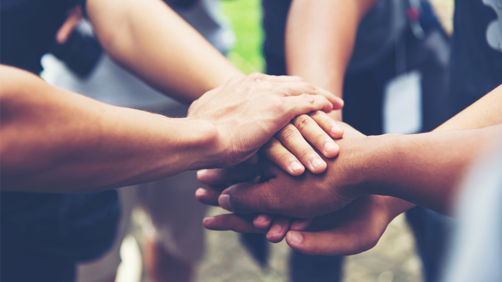 In a symbol image, the hands of people of different colours.