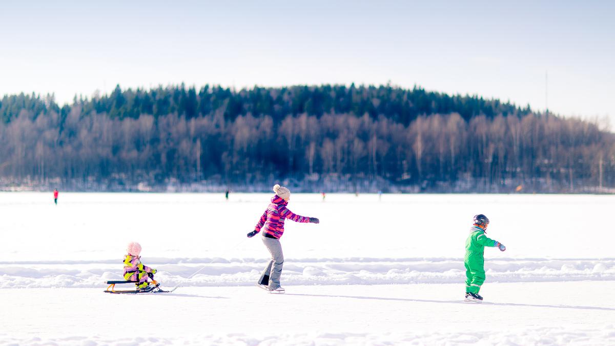 Ihmisiä luistelemassa jäällä talvisessa ympäristössä.